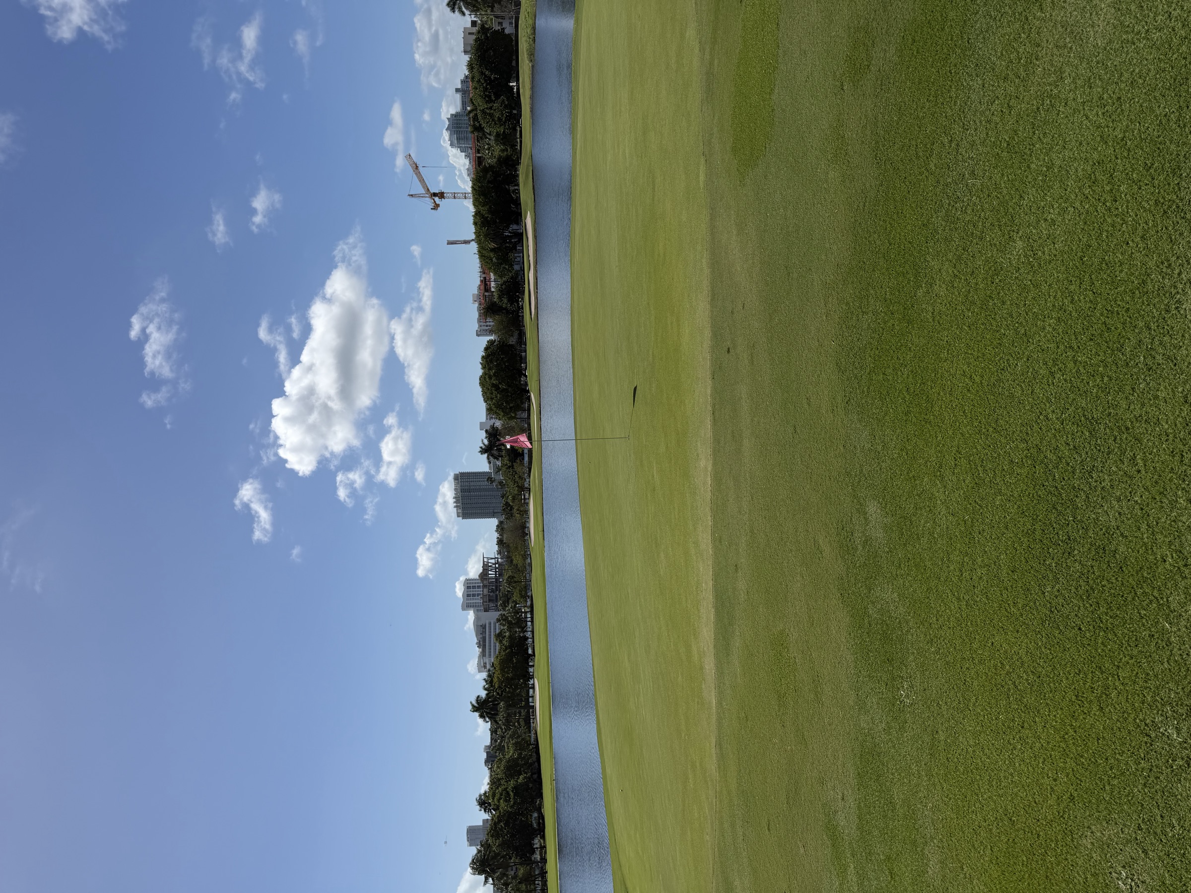 A green guarded by water at Miami Beach Golf Club, with the skyline beyond
